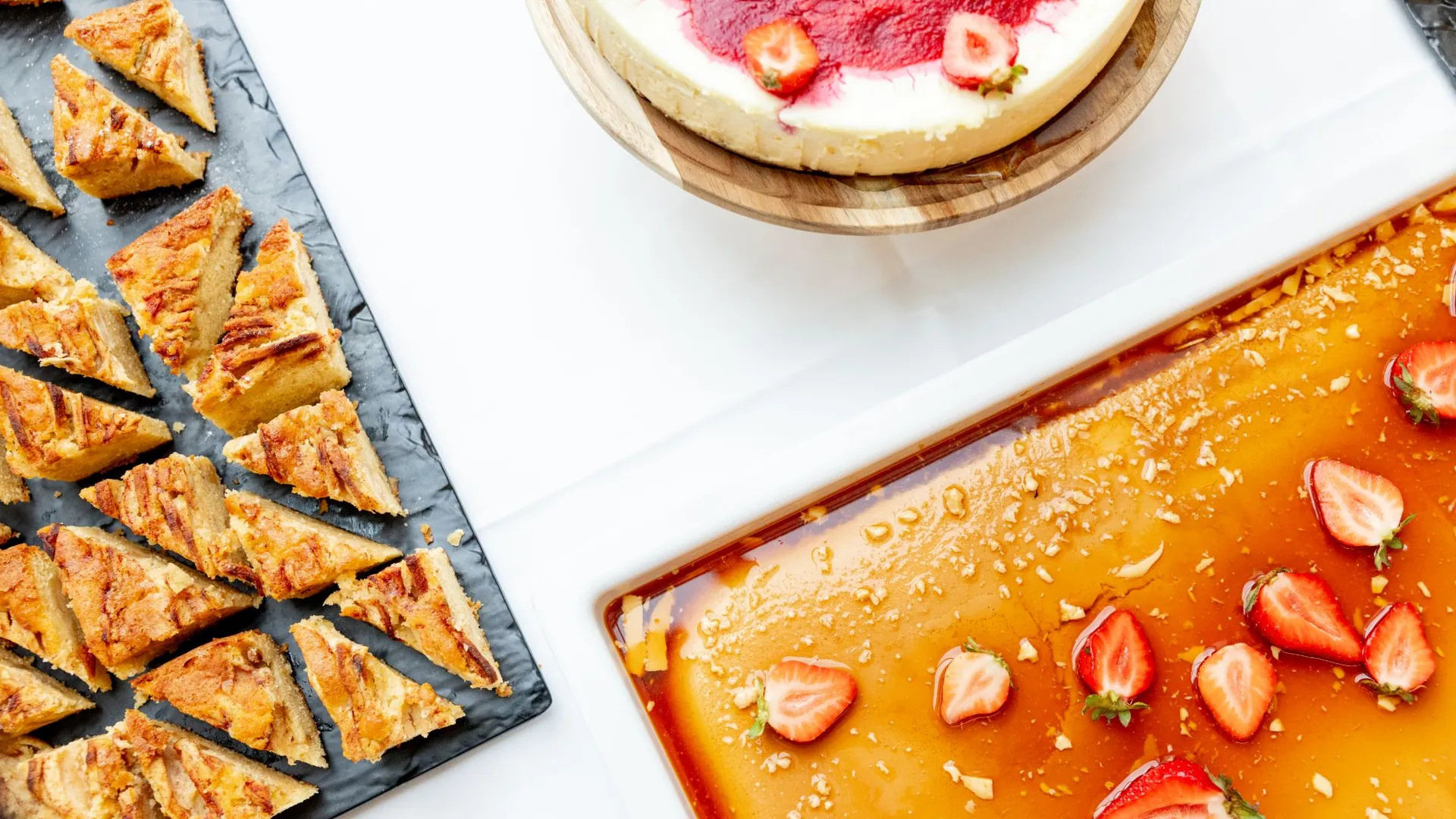 Dessertbord sett ovenfra: kake, ostekake og karamellpudding med jordbær